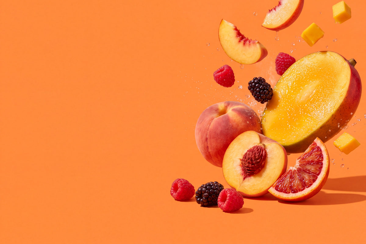 Mango, Pfirsich, Blutorange, Himbeeren und Brombeeren schweben vor mangoorangem Grund